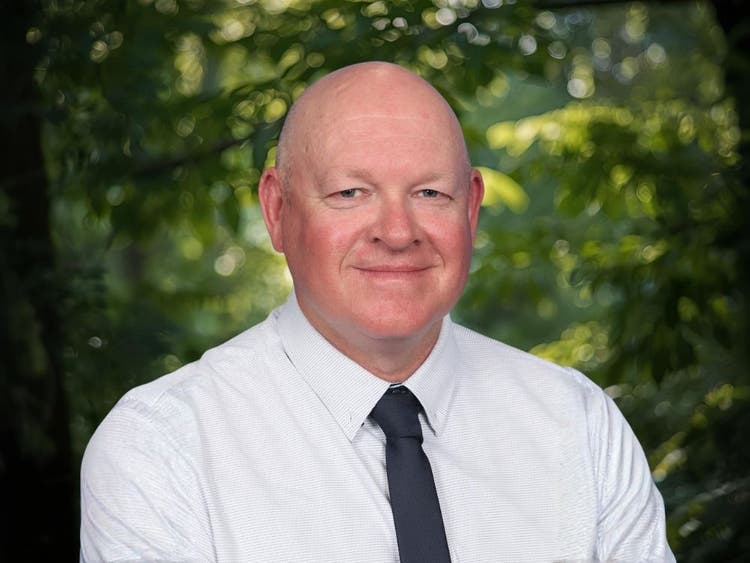 Photo of relieving executive principal in front of trees